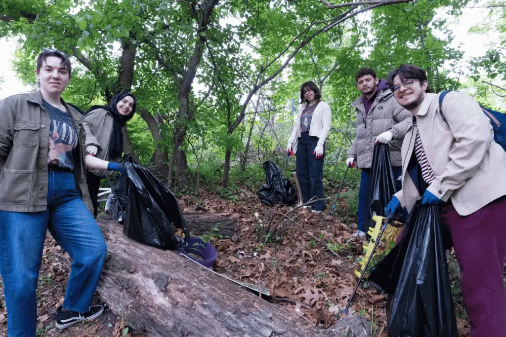 BAU Program Images (78) Volunteers clean a forest area, holding trash bags and pickers, promoting environmental conservation.