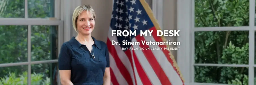 President of Bay Atlantic University with U.S. flag and greenery background.