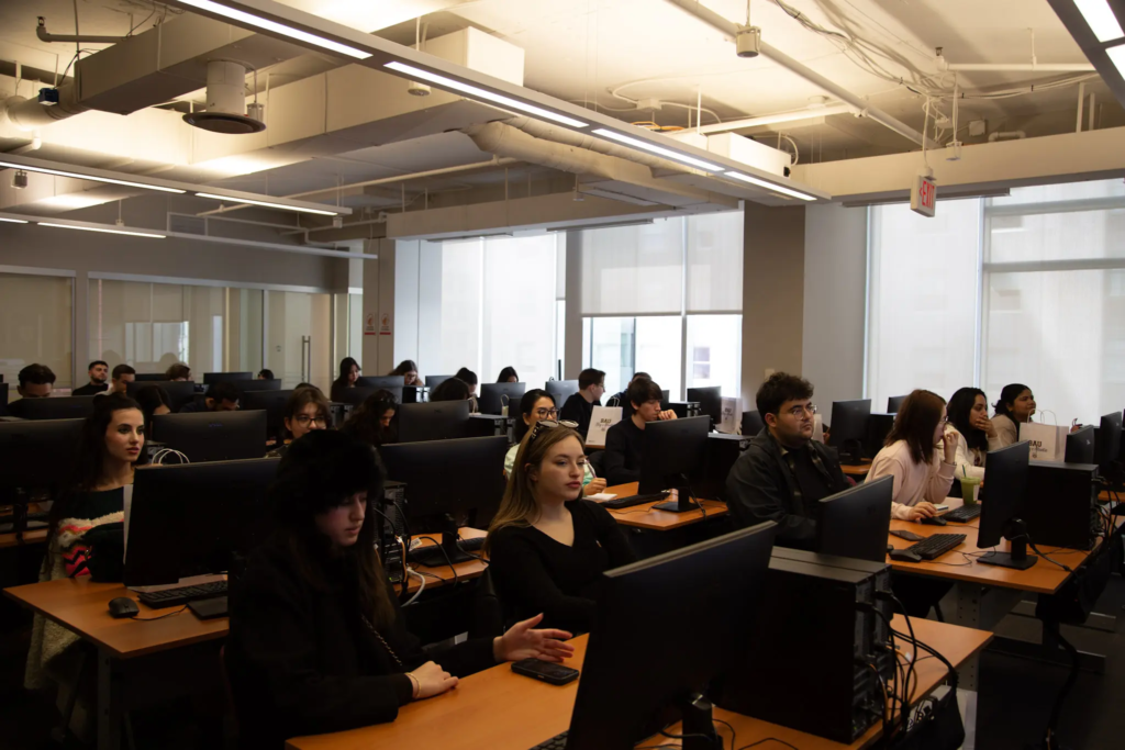 154-KQ9A0157 A classroom of students focused on computer screens, learning in a modern educational environment.