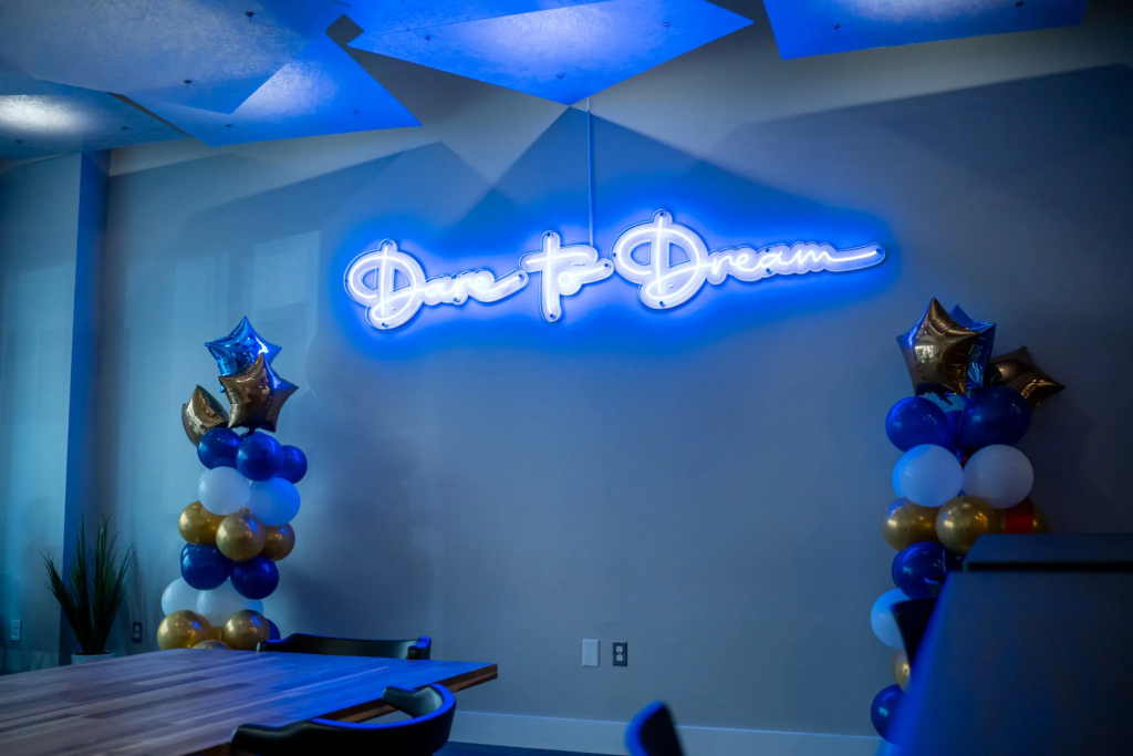 DSC06480 Neon sign Dare to Dream with colorful balloon clusters in a dimly lit room.