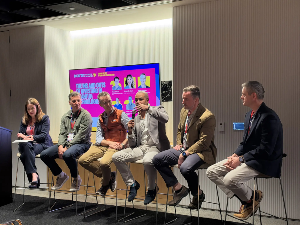 Panel discussion on investing in quantum technology, featuring five experts on a modern conference stage.
