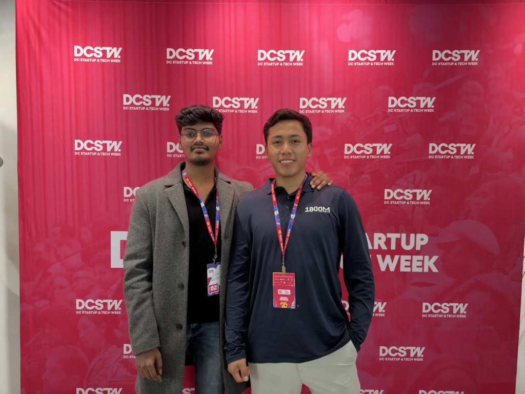 Two attendees at DC Startup Week event pose in front of a branded backdrop.