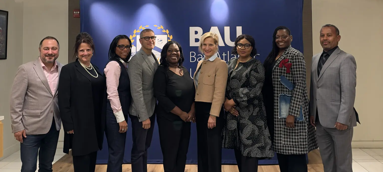 Group of professionals posing in front of a blue backdrop at a business event in an office setting.