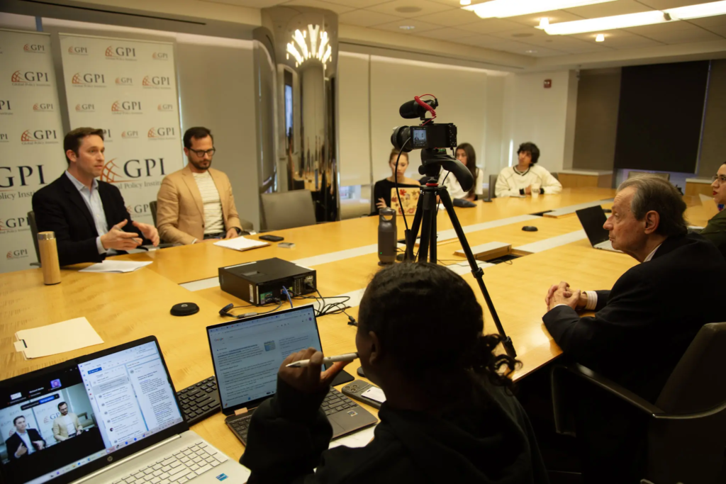 KQ9A0001 Meeting at GPI office with participants discussing and filming, laptops visible on the conference table.